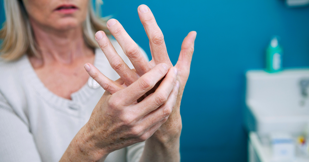 ältere Frau mit Rheumabeschwerden an der Hand
